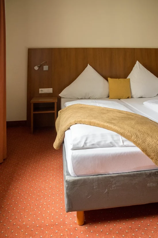 Doppelbett im Hotelzimmer, weiße Bettwäsche und Wolldecke